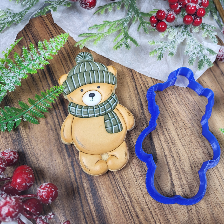 Winter teddy bear cookie with scarf next to matching cookie cutter